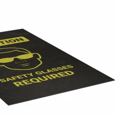 This 3 ft x 5 ft polypropylene entrance mat with adhesive backing communicates the mandatory safety glasses requirement at facility entry points. The 1/8 in thick mat is designed for indoor use in industrial plants, warehouses, and laboratories where eye protection is required before entering designated areas.