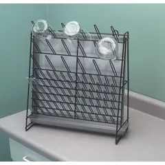 This steel benchtop drying rack is designed for air-drying laboratory glassware, plasticware, and equipment after washing. It includes a draining pan to collect runoff and features 3-inch pegs for holding items. Overall dimensions: 18 1/4 in length, 7 1/8 in width, 18 1/4 in height.