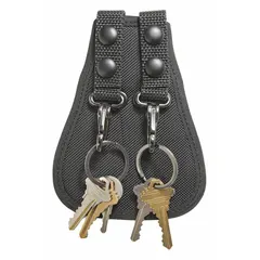 This key holder is constructed from ballistic nylon and features a snap closure. It measures 5 inches by 115 mm and fits belts up to 2 1/4 inches wide. Suitable for organizing and securing keys on a belt in security, maintenance, or facility management settings.