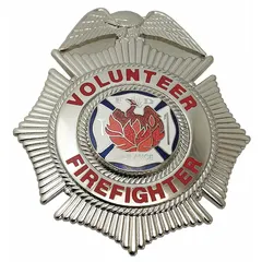 This metal badge features a cross design and is finished in silver. It measures 2 1/2 inches by 3 inches and is constructed from metal. The badge includes a pin and safety catch for attachment to uniforms or gear. Typical applications include identification and recognition for volunteer firefighters.