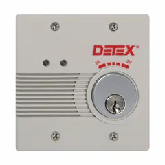 This standard door alarm features a gray plastic body with a mortise cylinder. It is electrically corded and produces a 100 dB horn sound. Typical applications include securing emergency exit doors in commercial and industrial settings.