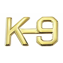 Metallic rank insignia featuring a K-9 design in gold finish. Measures 1/2 inch and attaches via clutch pin. Suitable for uniform wear on caps, collars, or lapels to indicate canine-handler roles.
