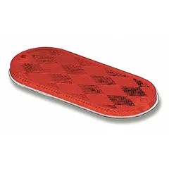 Red oval stick-on reflector with acrylic construction, 4 3/8 in overall length and 1 7/8 in overall width. Complies with FMVSS standards. Used on trailers, trucks, and heavy equipment for side and rear visibility marking.