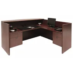 This L-shaped reception desk is constructed from mahogany melamine, offering a professional appearance for front-office and lobby areas. With an overall height of 42 inches and width of 71 inches, it provides a functional workstation for greeting visitors and managing administrative tasks.