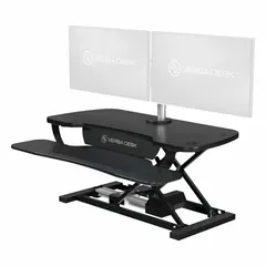 This electronic standing desk converter features a black wood desktop measuring 40 inches wide by 24 inches deep. It allows users to alternate between sitting and standing positions, promoting ergonomic comfort in office or industrial settings.