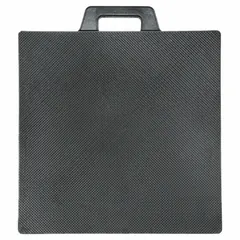 Square black rubber outrigger pad with molded-in handles. Measures 18 in length, 18 in width, and 2 in thickness. Designed to distribute load from mobile equipment such as cranes and aerial lifts, preventing sinking or tipping on soft ground.